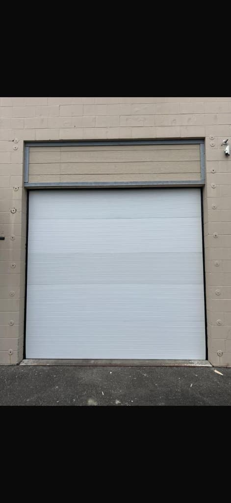 White commercial sectional garage door on a cinder block building in Portland and Salem Metro — Commercial Garage Doors